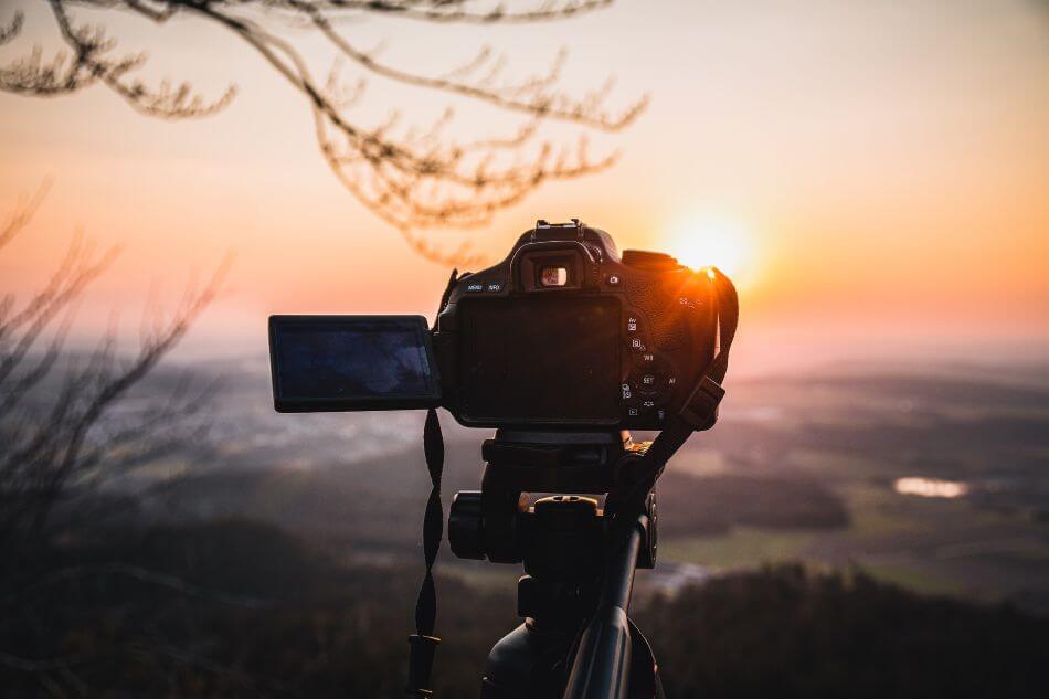 camera on a tripod in front of a sunset
