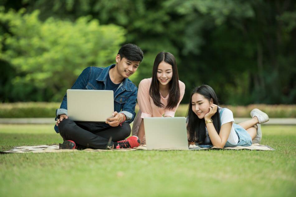 students on grass with laptops